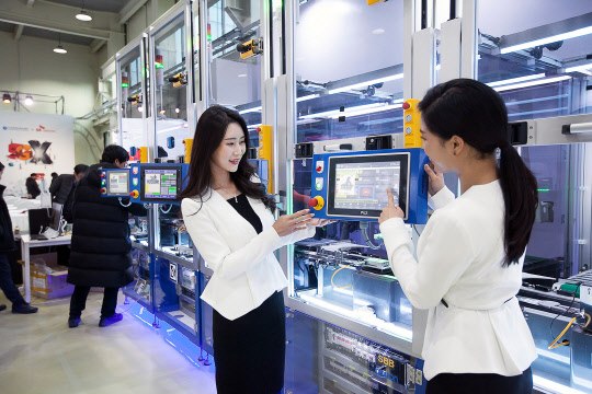 SK텔레콤모델들이 5G 스마트 유연생산 설비를 통해 소형IoT 기기가 만들어지는 과정을 지켜보고 있다. SK텔레콤 제공
